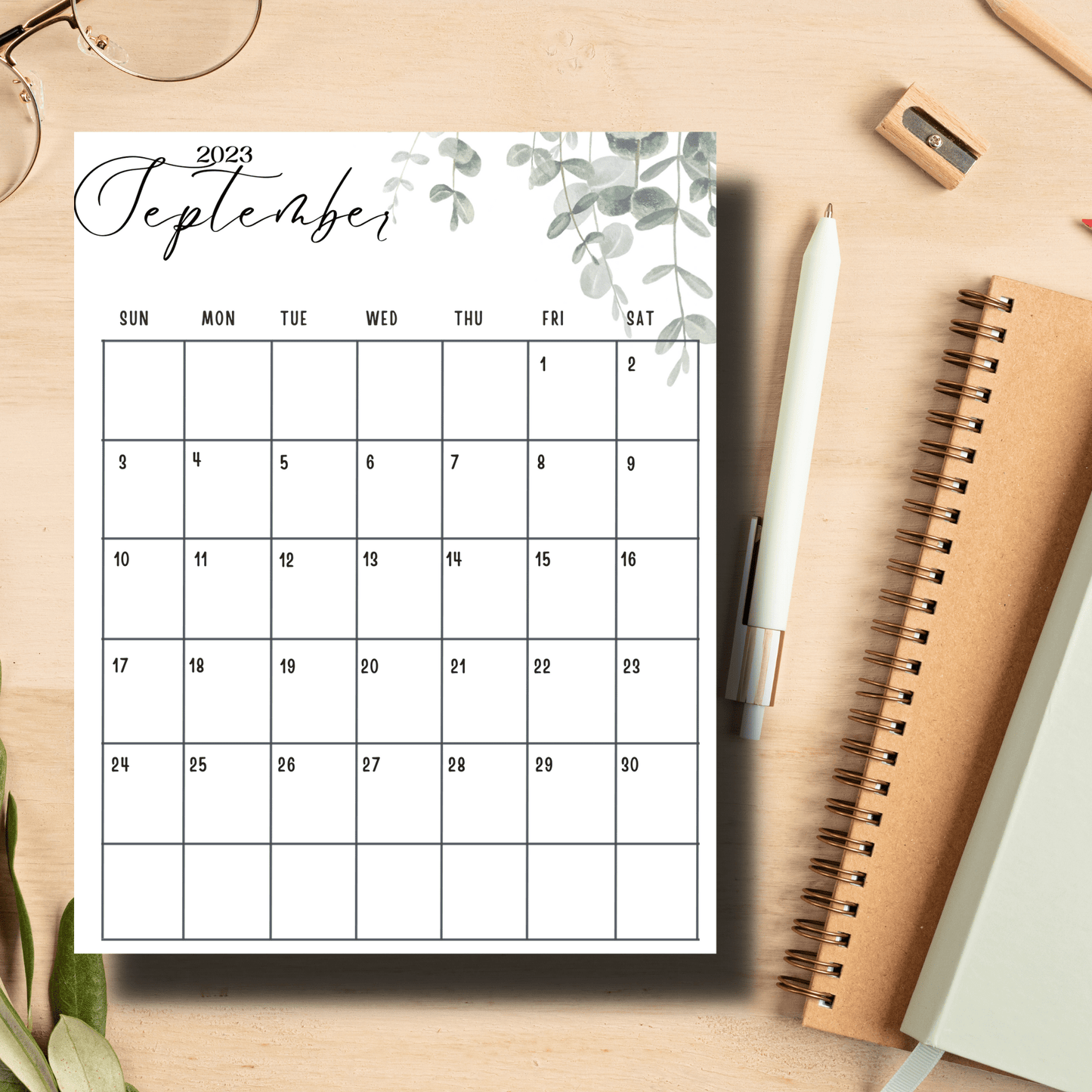 a4 printed september 2023 calendar paper with notebooks and pen on a table