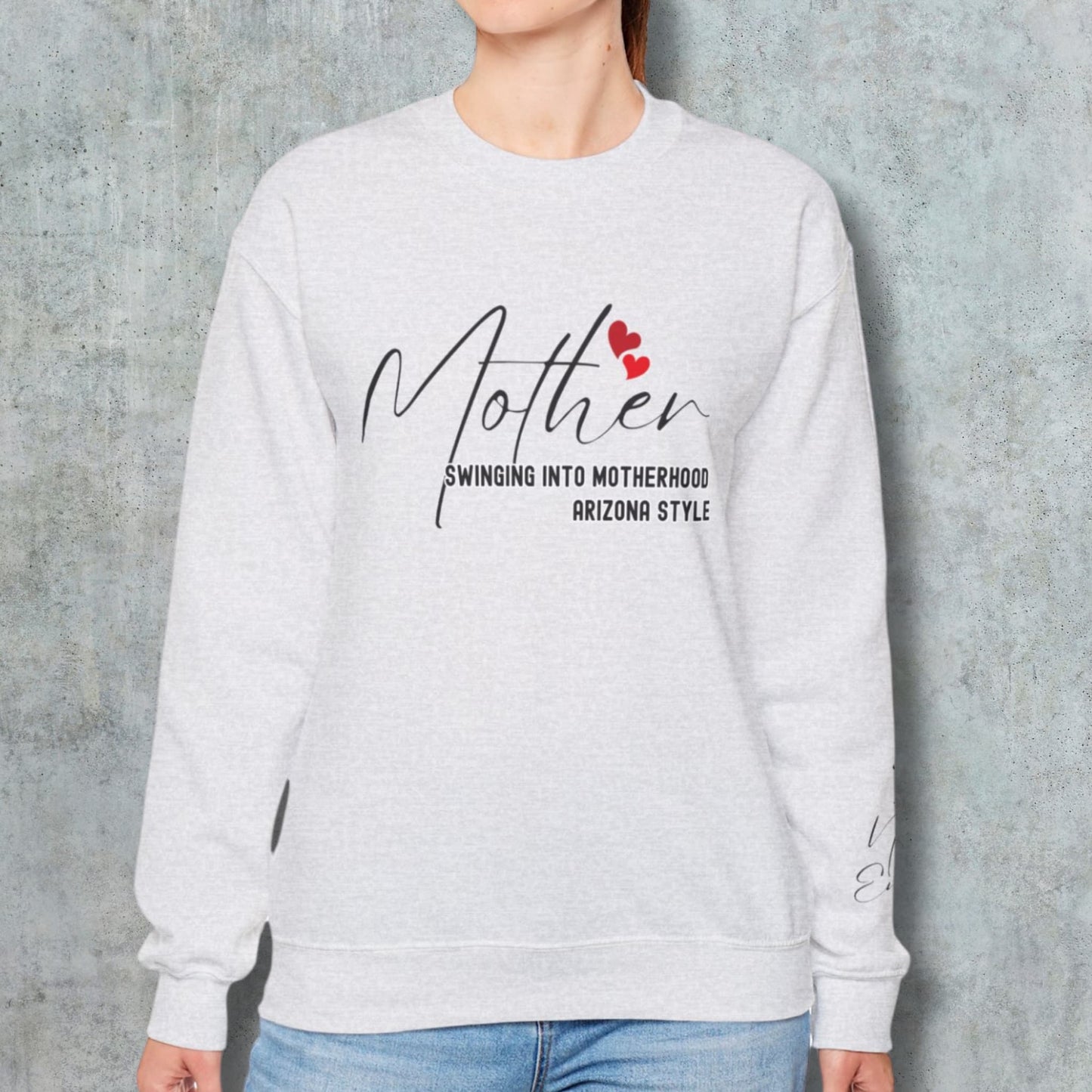 Woman modeling the Custom Baseball Mom Crewneck Sweatshirt with a wall background, highlighting the fit and Arizona style design.Custom Baseball Mom Arizona Style Sweatshirt displayed on a wooden surface, accompanied by flowers and women's accessories, creating an elegant flatlay.