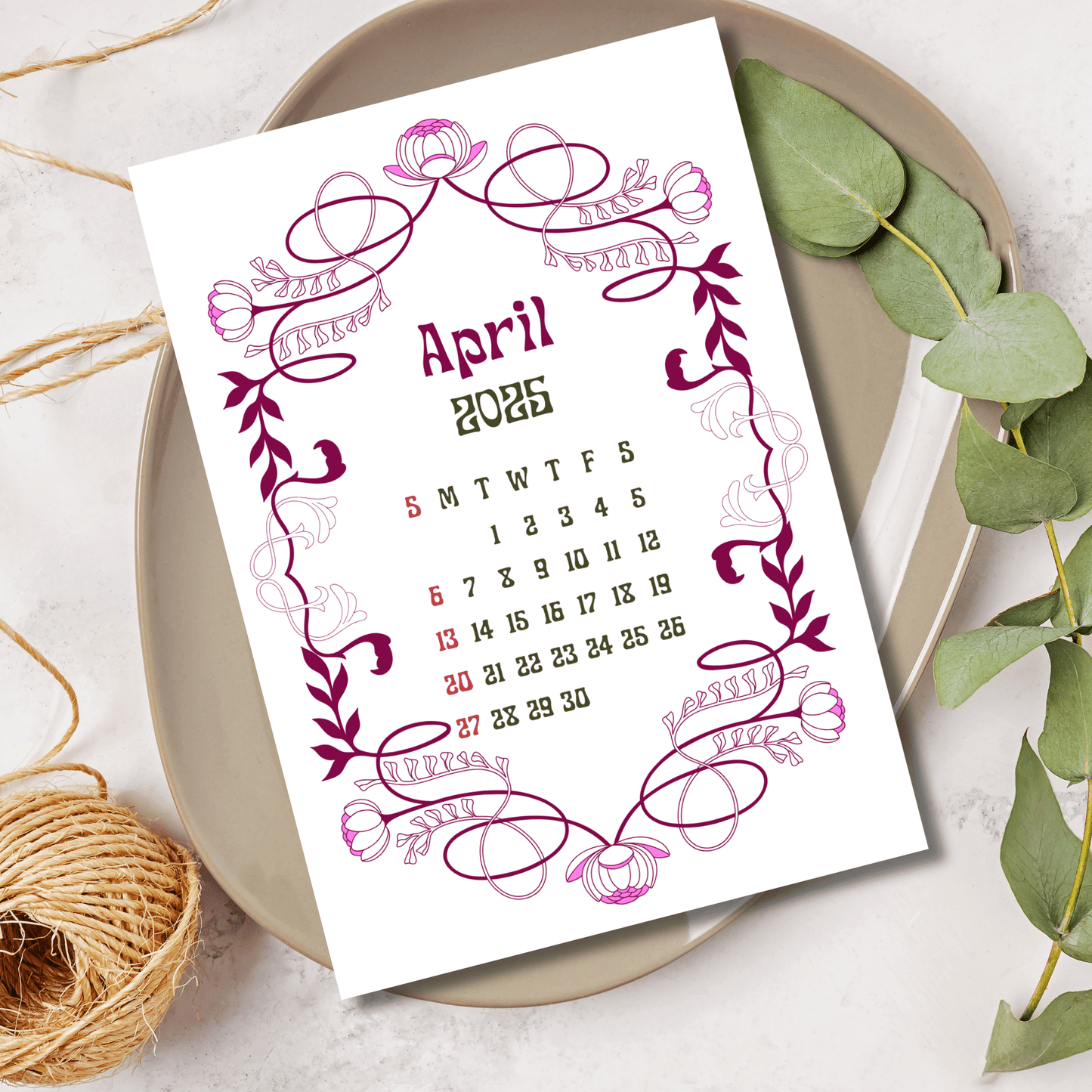 April 2025 calendar page featuring magenta Art Nouveau floral border with swirling tulips and leaves, styled with eucalyptus and twine on ceramic plate