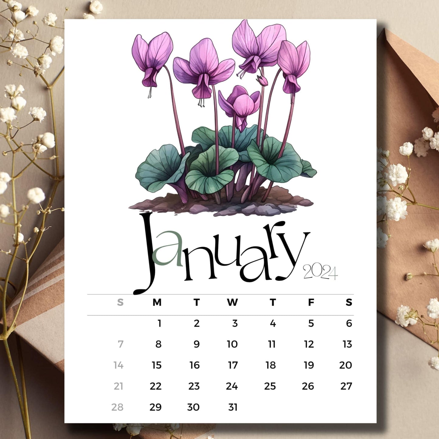 Cyclamen Charm January 2024 full year calendar on a table with an envelope and small white flowers.
