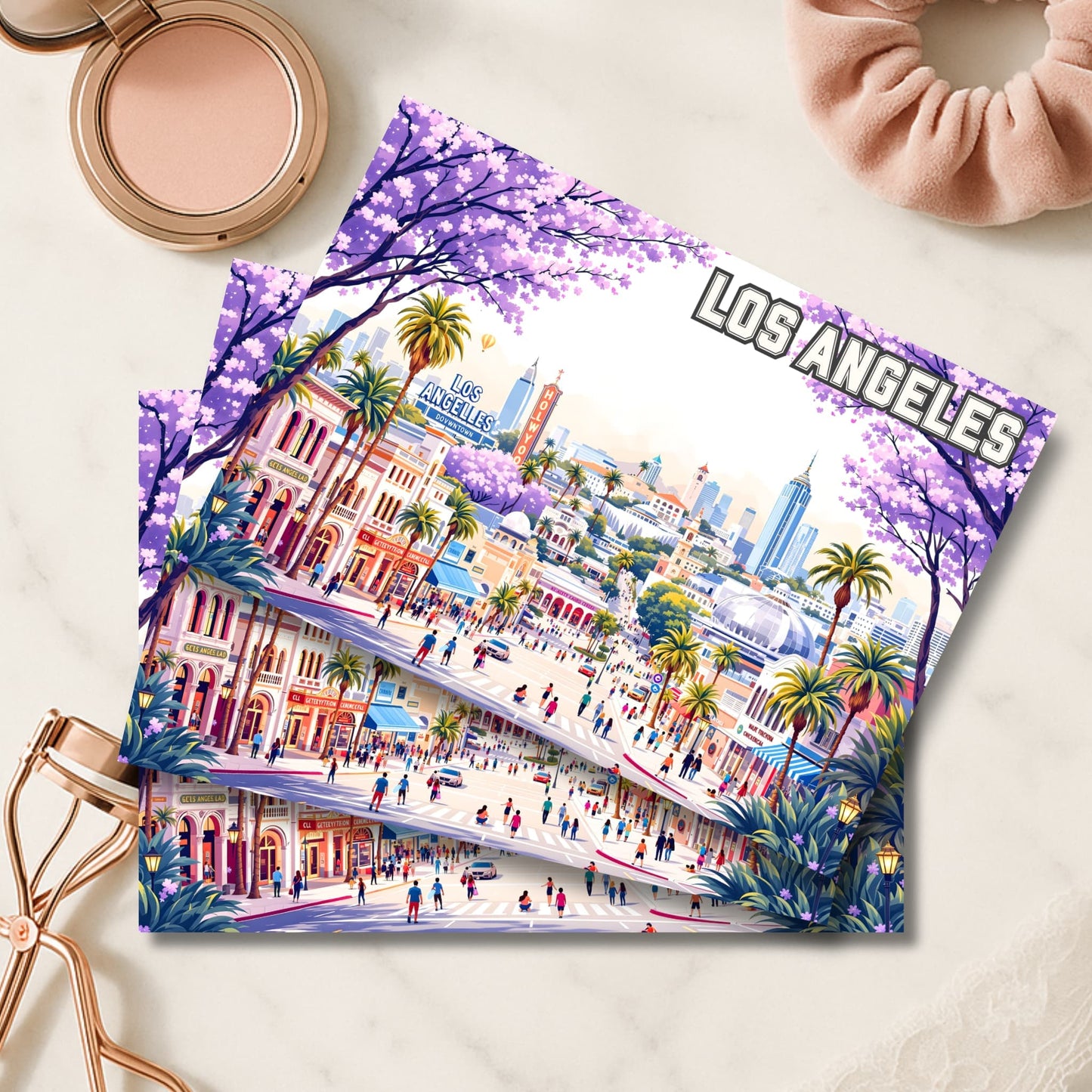 Los Angeles illustrated art prints with purple jacaranda trees and downtown skyline beside rose gold makeup