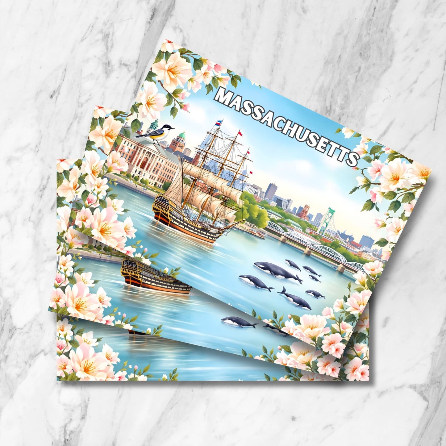Stack of Massachusetts Boston Harbor prints with USS Constitution, whales, chickadee bird and mayflower blossoms on marble background.