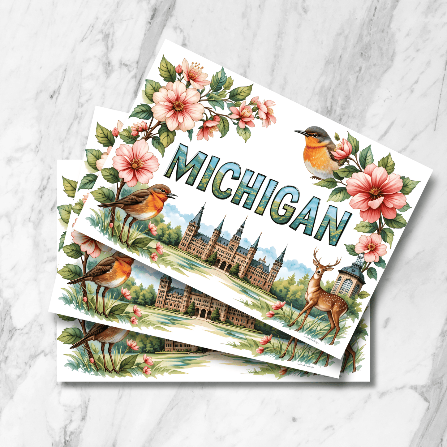 tack of Michigan state postcards featuring robin, deer, apple blossoms and historic architecture arranged with detailed floral borders on marble surface.