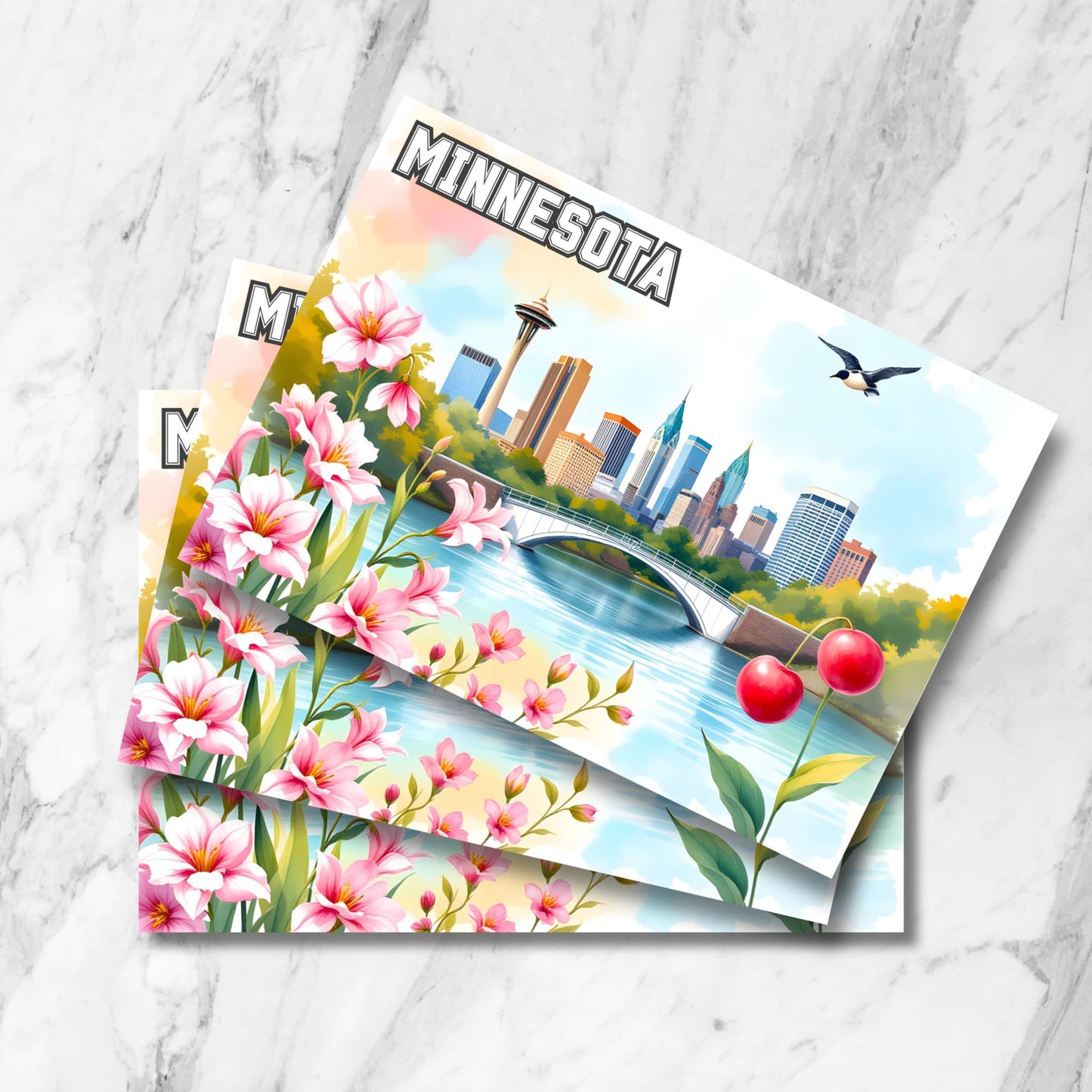 Stack of Minnesota postcards featuring city skyline, bridge, pink flowers, loon bird and red cherries on marble background.