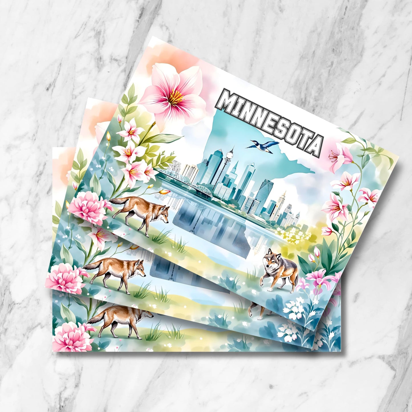 Stack of Minnesota postcards featuring Minneapolis skyline, state outline, wolves, loon and pink flowers on marble background.