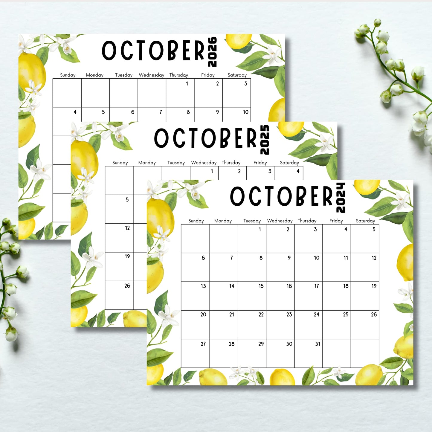 Three October calendars with lemon design on light blue background. White floral sprigs visible in corner, emphasizing the botanical theme.