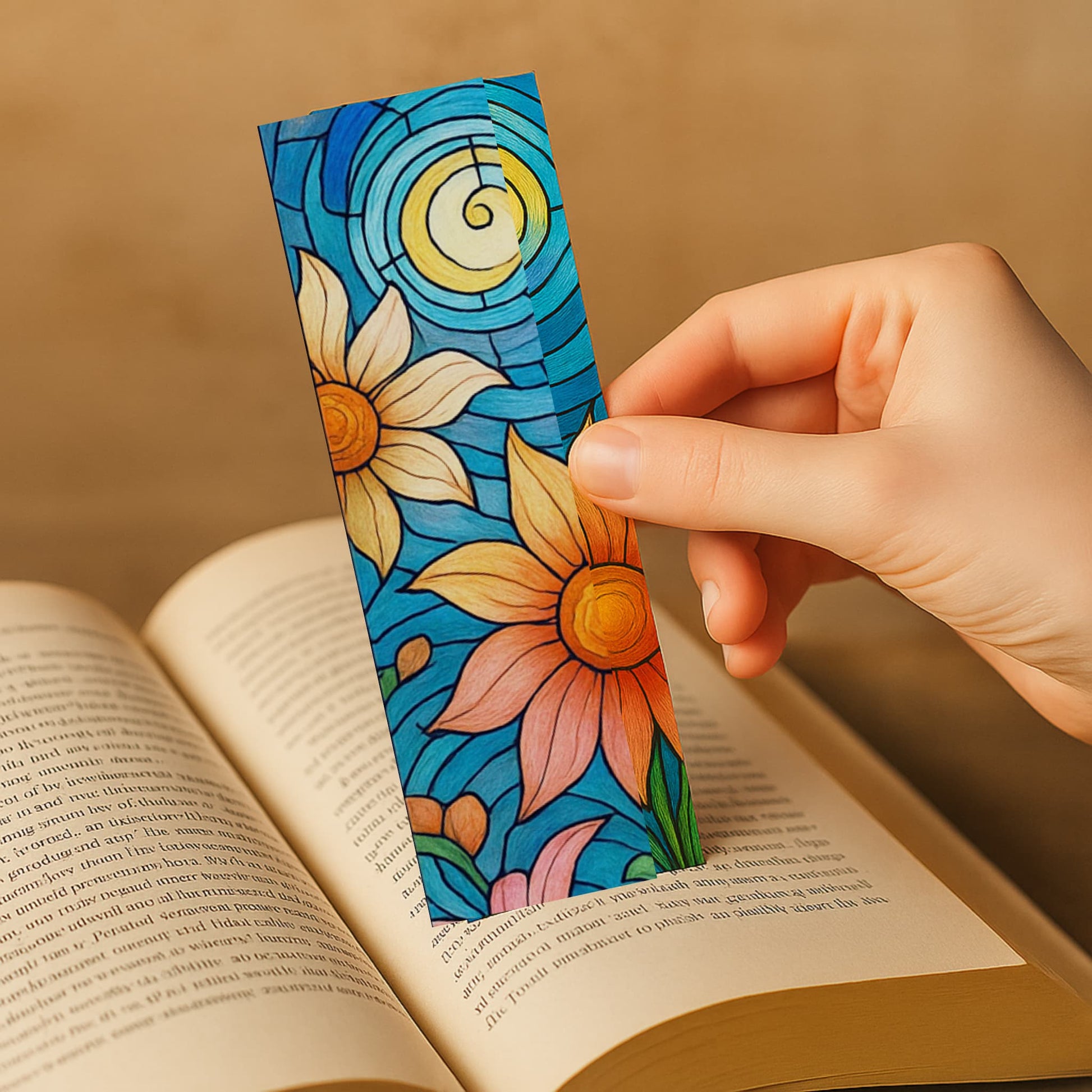 Hand holding colorful sunflower and daisy stained glass bookmark against open book pages