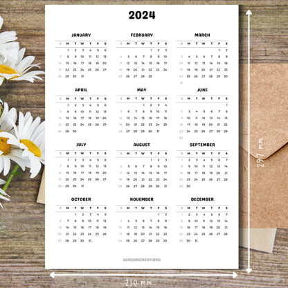 Printed page of 2024 calendar on a brown wooden desk with white flowers on the left side.