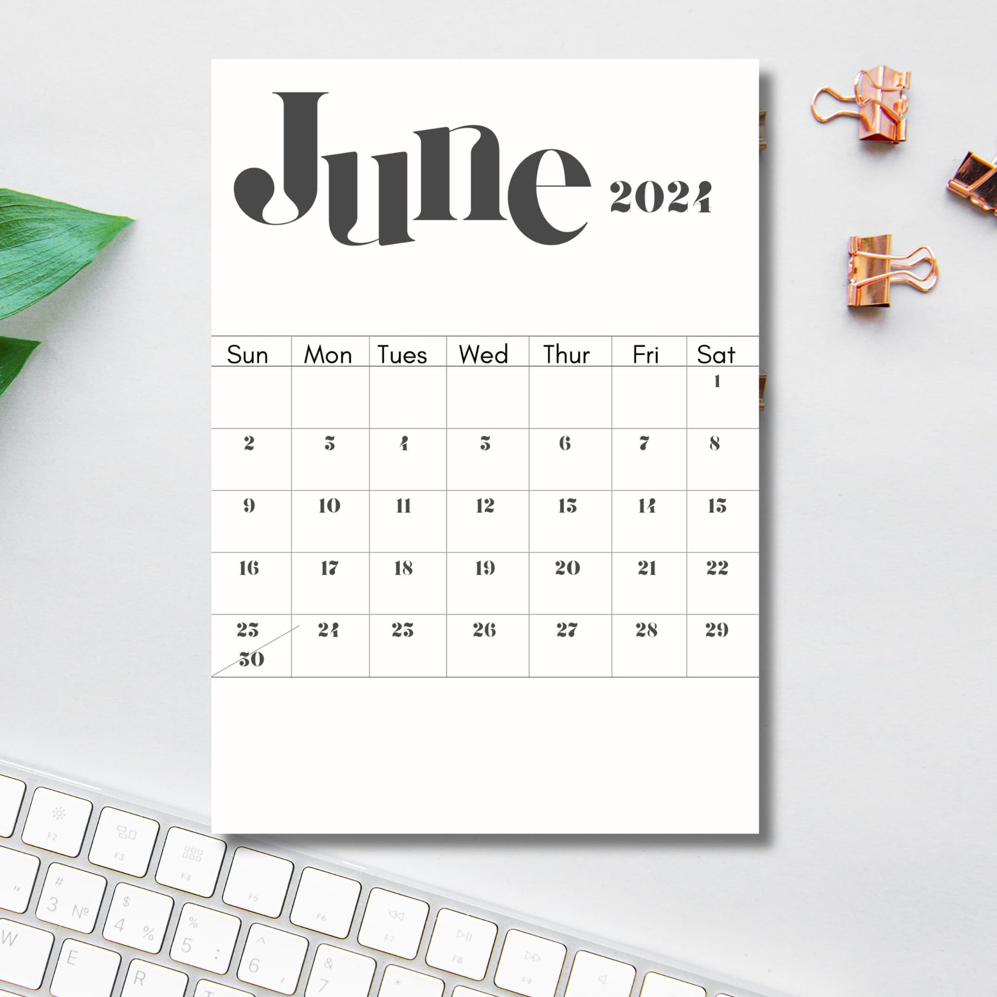 printed monthly 2024 June calendar on a table with office supplies and keyboard