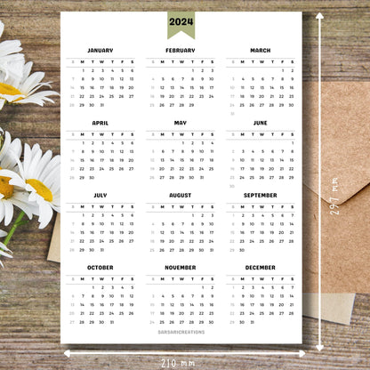 Minimalist 2024 calendar printed page on brown wooden desk with white flowers and size guide.