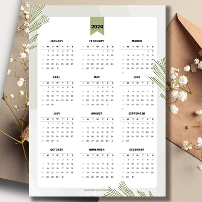 Nature-themed 2024 full year calendar on a table with envelope and small white flowers in the background.