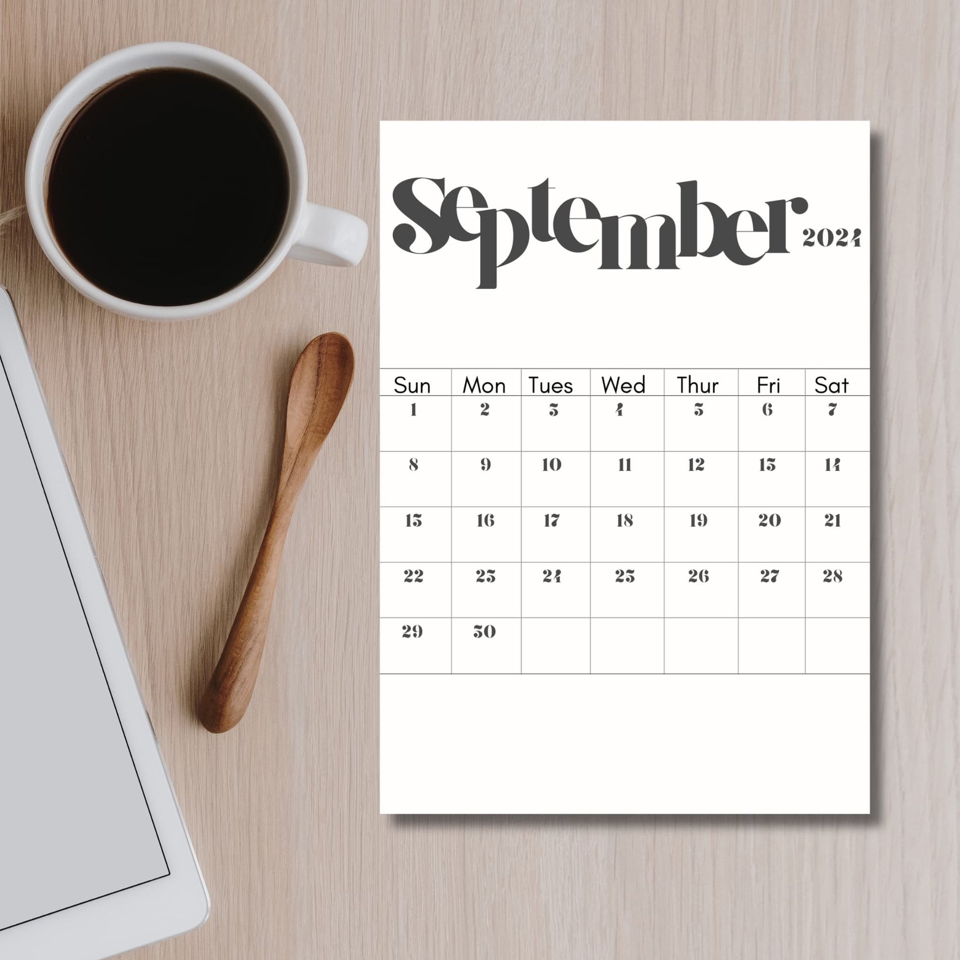 2024 September calendar print on brown table with coffee cup and spoon