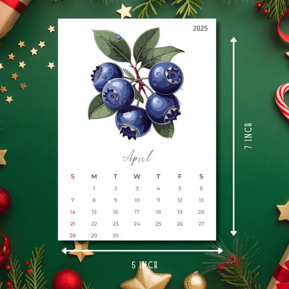 April 2025 calendar page with watercolor blueberry illustration, showing 5x7 inch size reference, displayed on festive green background with golden stars and Christmas decorations