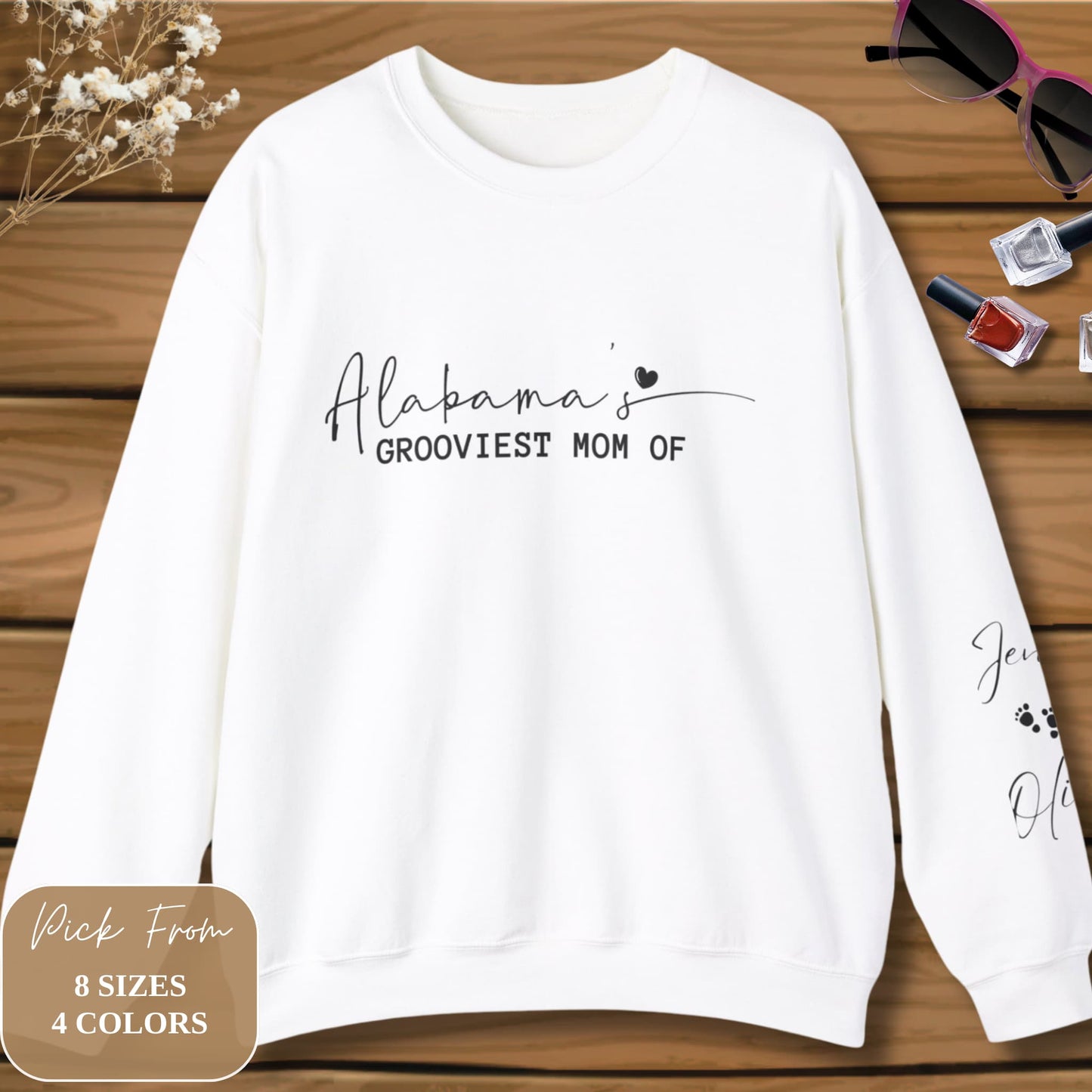 Alabama's Custom Mom Crewneck Sweatshirt displayed on a wooden surface, complemented by flowers and women's accessories in a stylish flatlay.