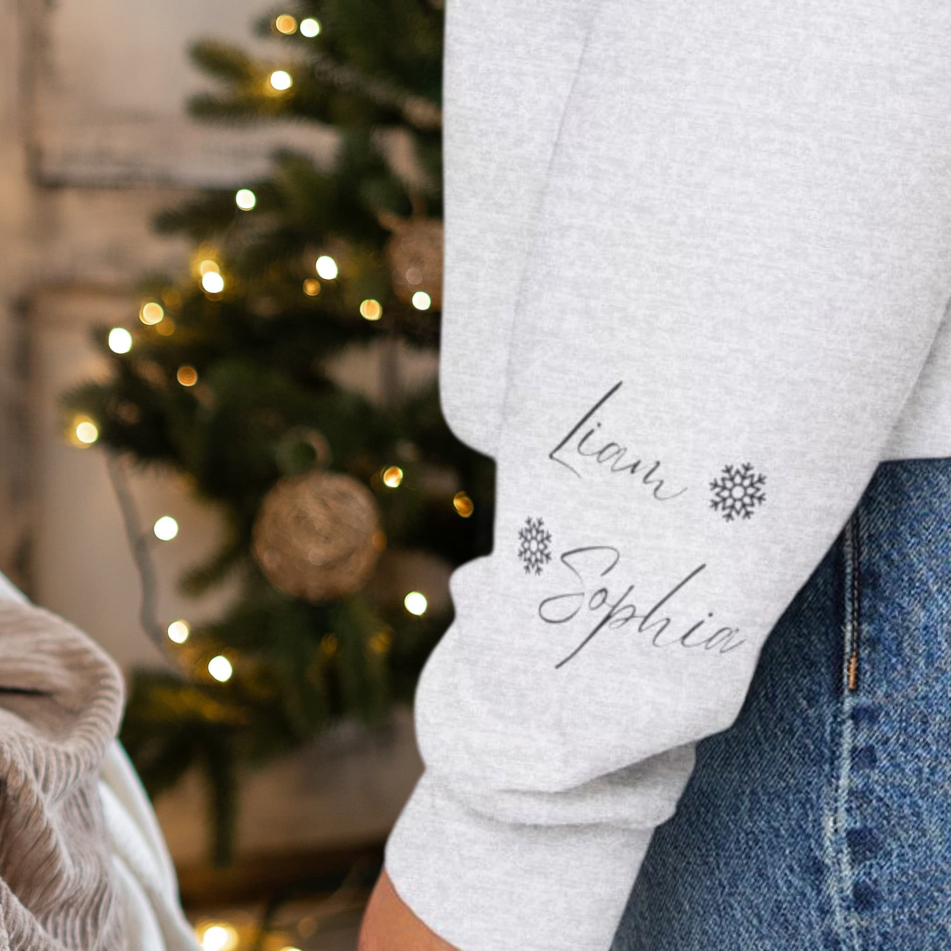 Close-up view of the sleeve design on the Alaskan Mother Personalized Crewneck Sweatshirt, emphasizing the personalized kids' names and snowflake motif.