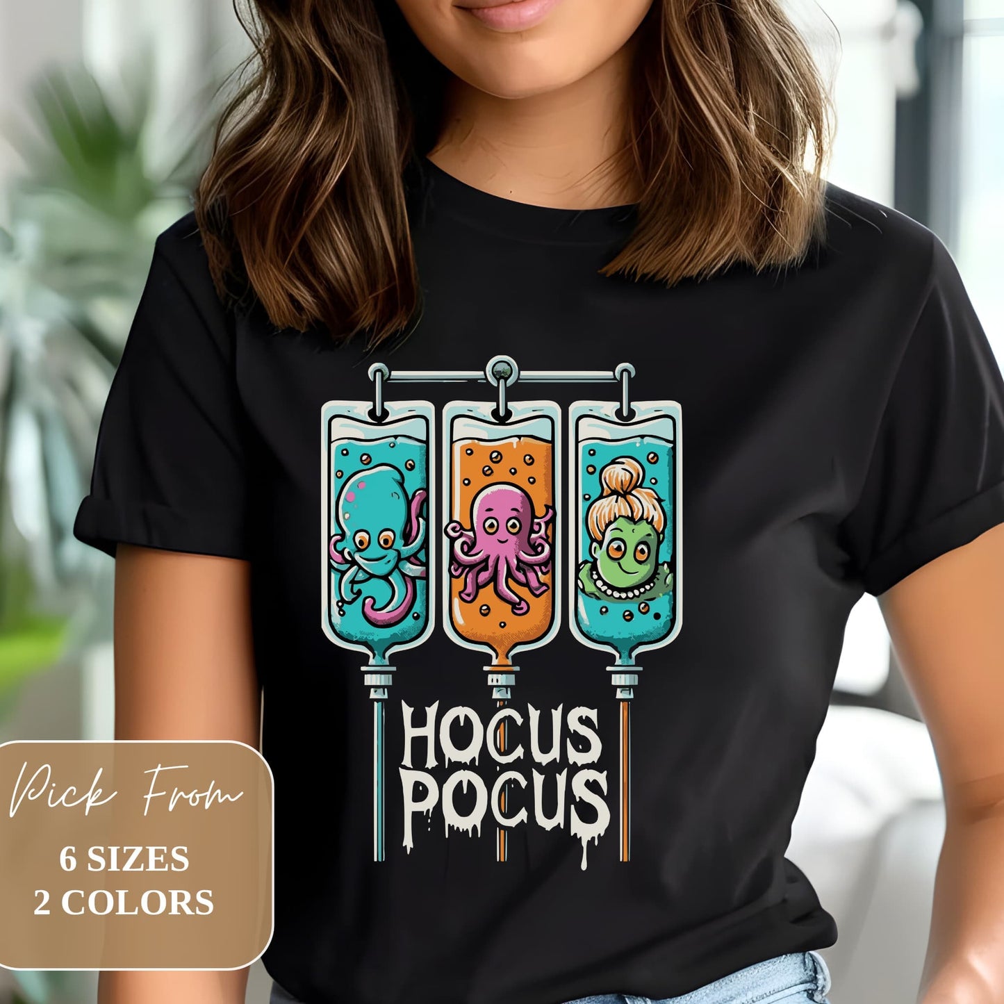 Woman wearing black t-shirt with 'Hocus Pocus' design showing three IV bags with playful sea creatures. Available in 6 sizes and 2 colors.