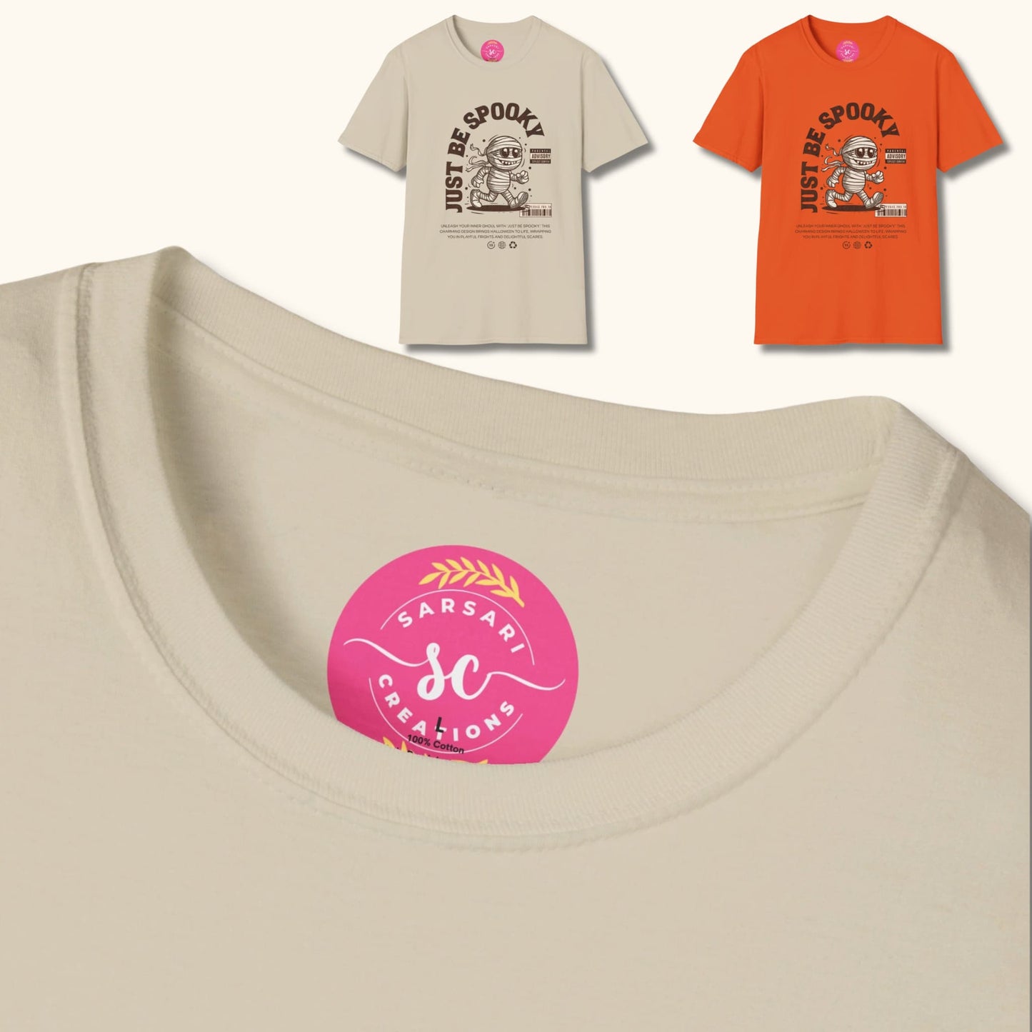 Two 'Just Be Spooky' t-shirts in beige and orange, featuring a cartoon mummy design. Close-up of Sarsari Creations label showing 100% cotton material.