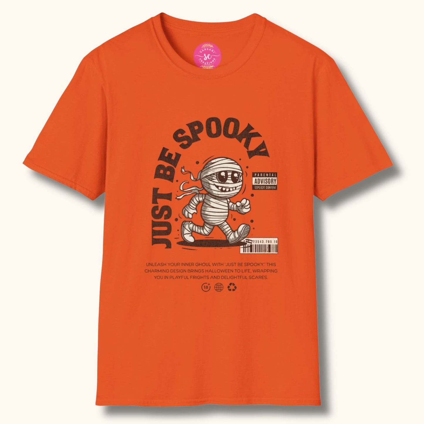 Orange t-shirt with 'Just Be Spooky' design featuring a cartoon mummy. Includes 'Parental Advisory' label and product description about Halloween frights and scares.