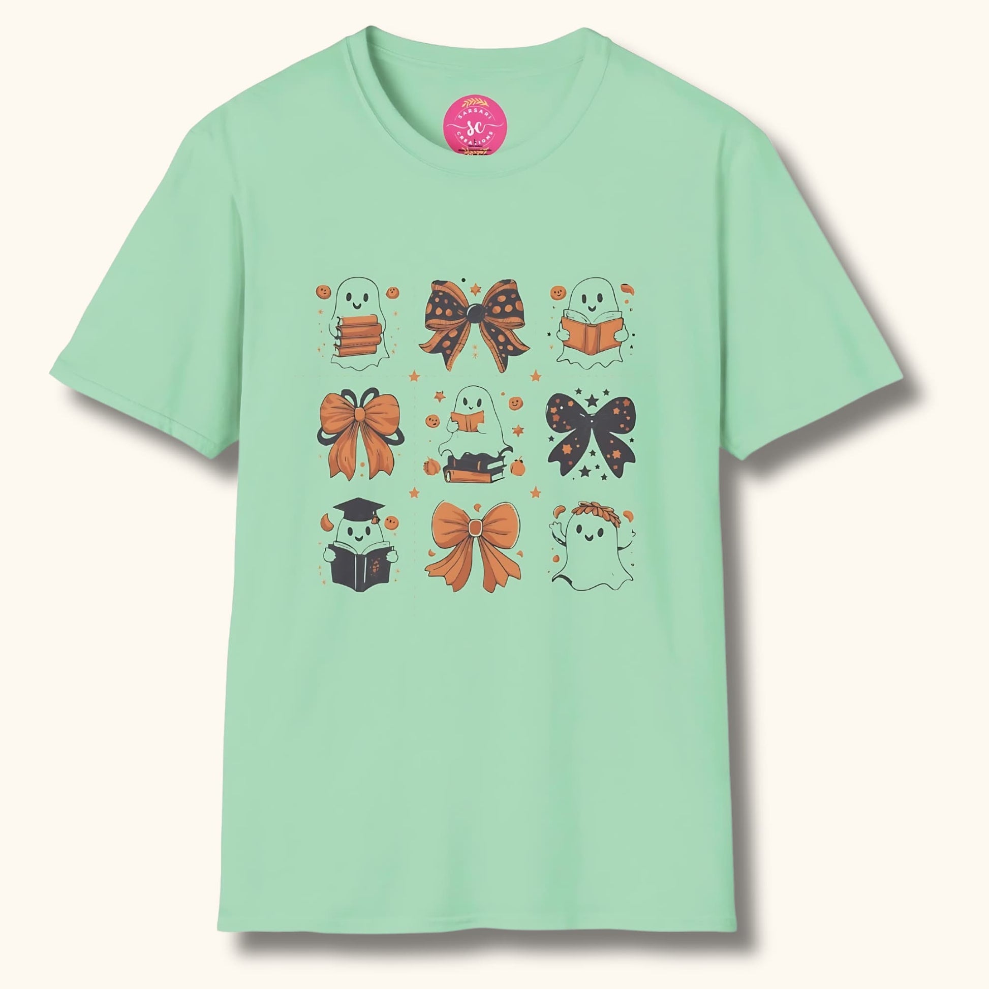 Mint green t-shirt with Halloween design: cute ghosts reading books, decorative bows, and stars. Sarsari Creations label visible.