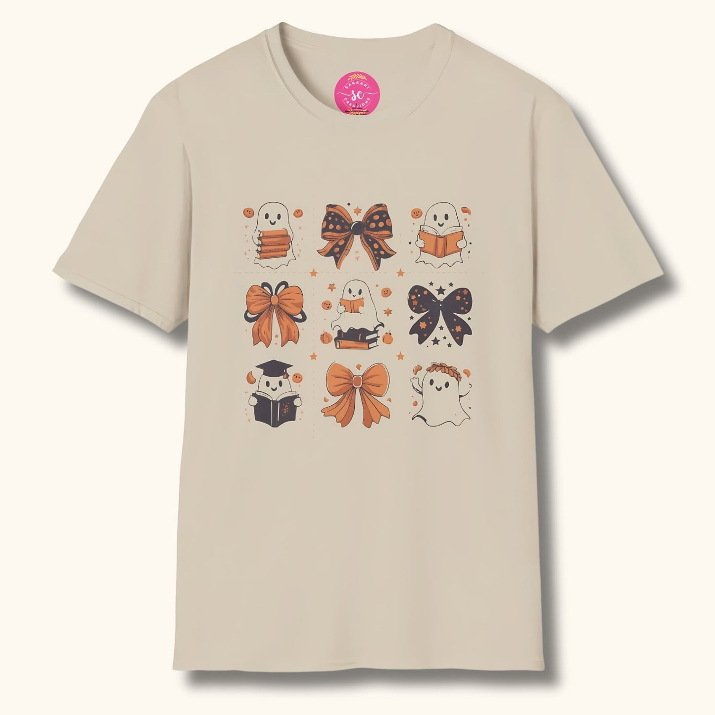 Sand-colored t-shirt with Halloween design: cute ghosts reading books, decorative bows, and stars. Sarsari Creations label visible.