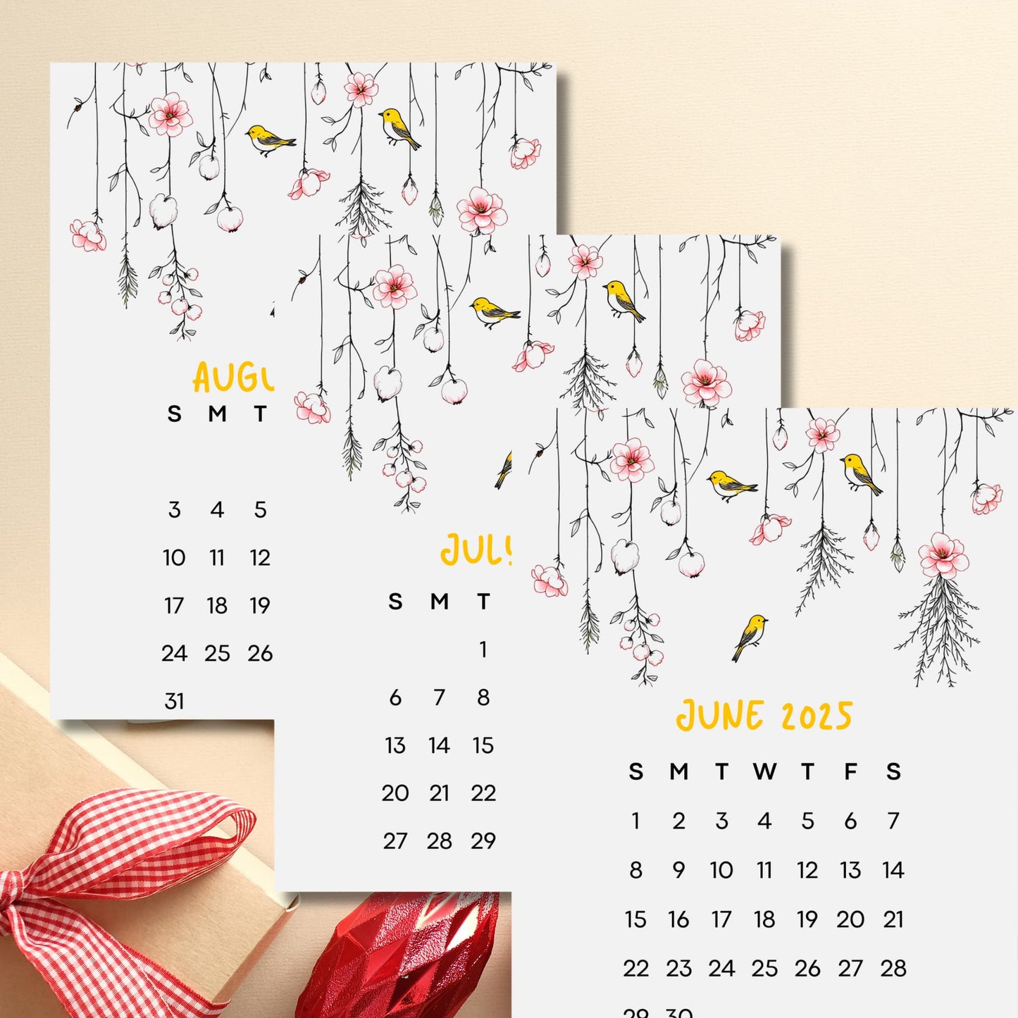 Stack of 2025 summer month calendar pages featuring yellow finches and hanging cherry blossoms, styled with red gingham ribbon accent