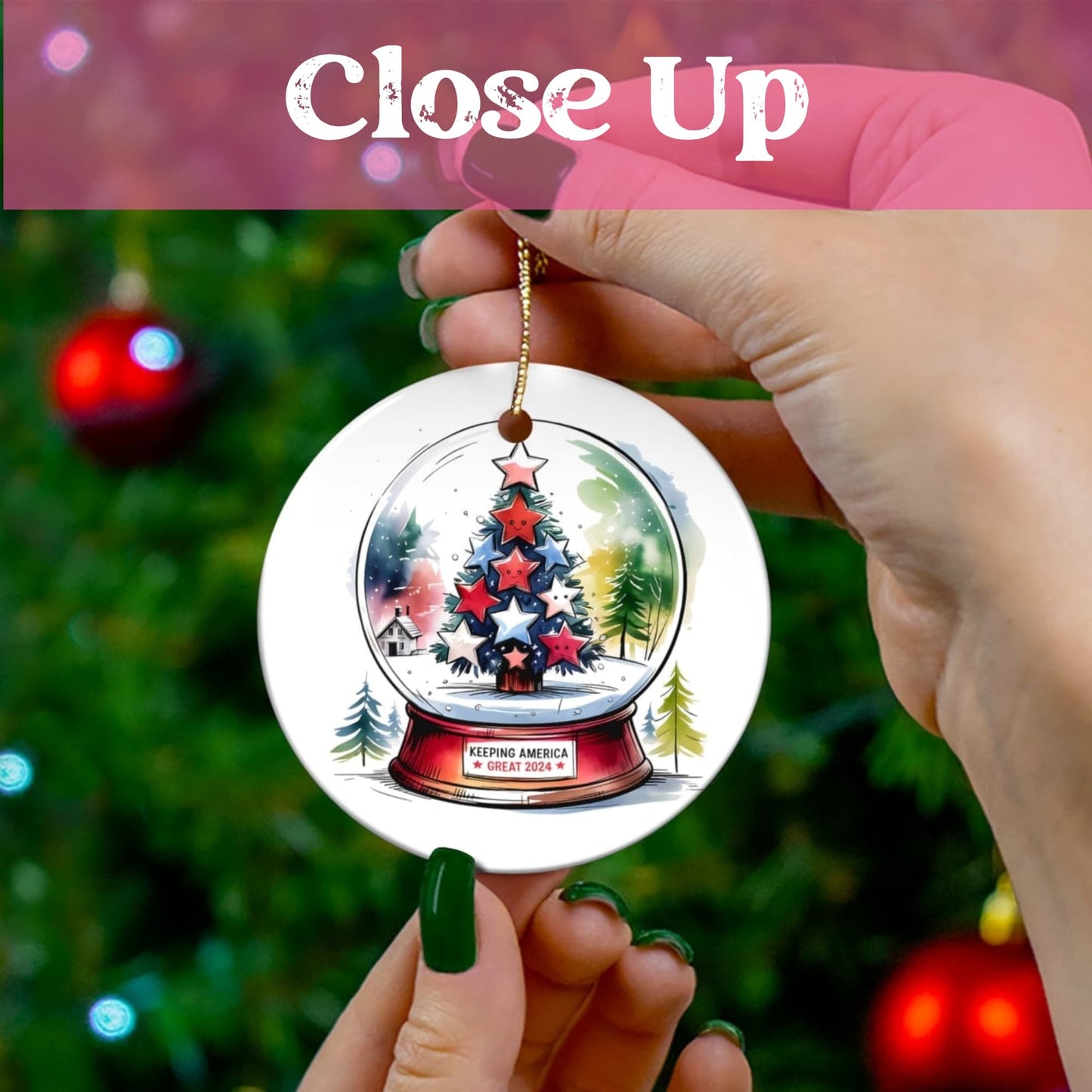 Hand-held display of ceramic ornament showing detailed snowglobe artwork with patriotic Christmas tree and winter landscape. Gold hanging string against festive background.