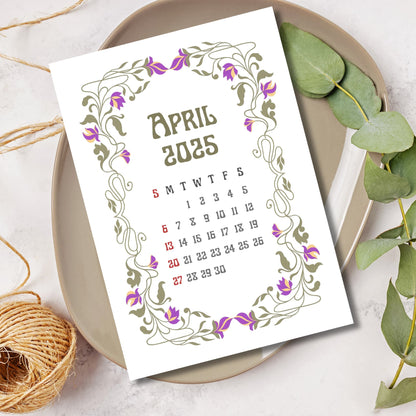 April 2025 calendar page featuring Art Nouveau frame with purple tulip motifs, styled with eucalyptus leaves and natural twine on ceramic plate