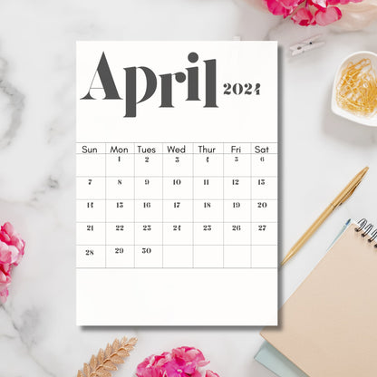2024 April calendar print on marble table with flower and staionary.