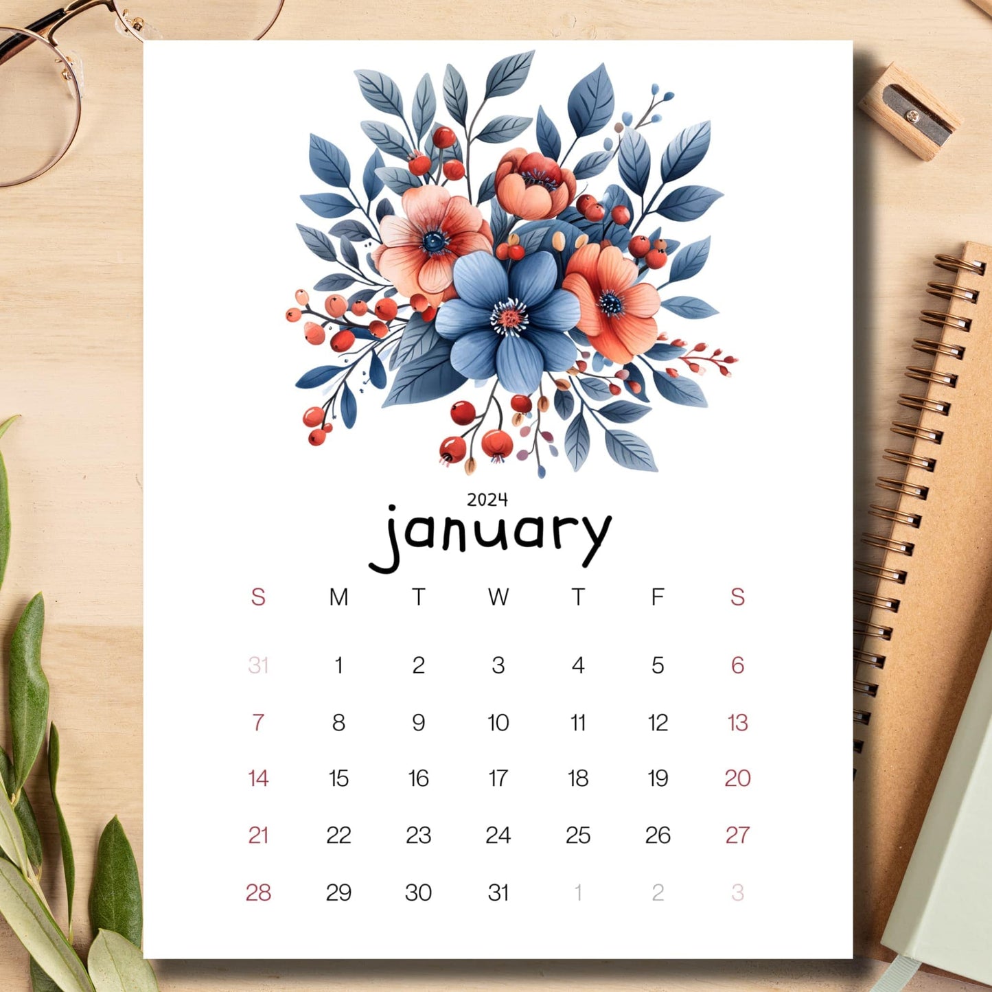 Berries and Blossoms January 2024 calendar laid on a light brown wooden desk with school supplies like a notebook, pencil, and sharpener.