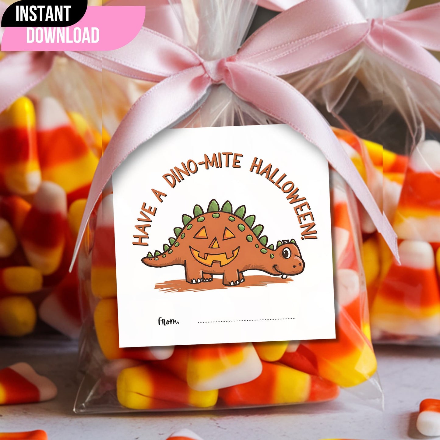 Cute dinosaur-shaped pumpkin Halloween gift tag attached to a candy bag with pink ribbon, showcasing "Have a Dino-mite Halloween" message