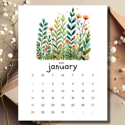 Evergreen Embrace January 2024 full year calendar on a table with an envelope and small white flowers.