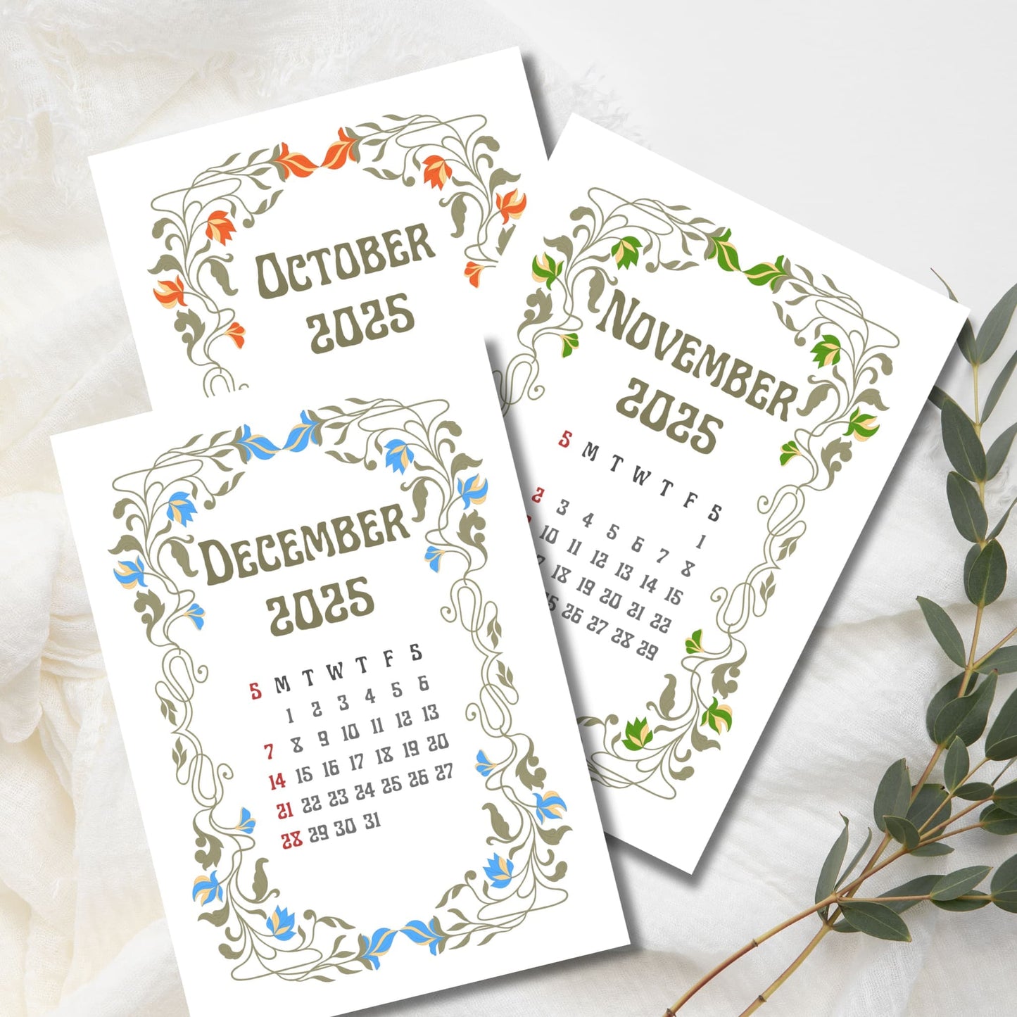 Three calendar pages for October, November, and December 2025 with Art Nouveau floral borders in seasonal colors - orange, green, and blue, styled with eucalyptus sprig on white fabric