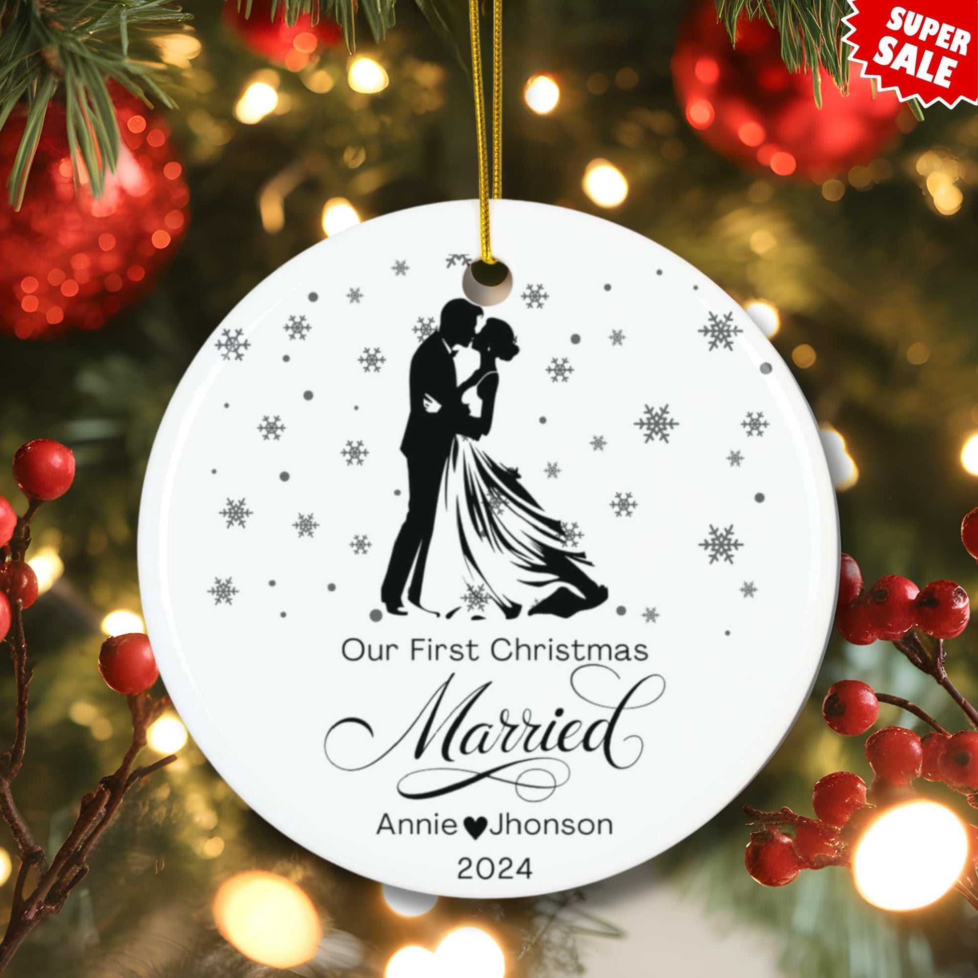 Festive lifestyle photo of personalized first Christmas married ornament hanging on Christmas tree with red berries, warm lights, and super sale badge