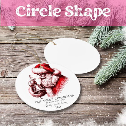 White ceramic circle ornament with red vintage Santa illustration holding bell, personalized text 'Our First Christmas as Family of Three 2024' on rustic wood background