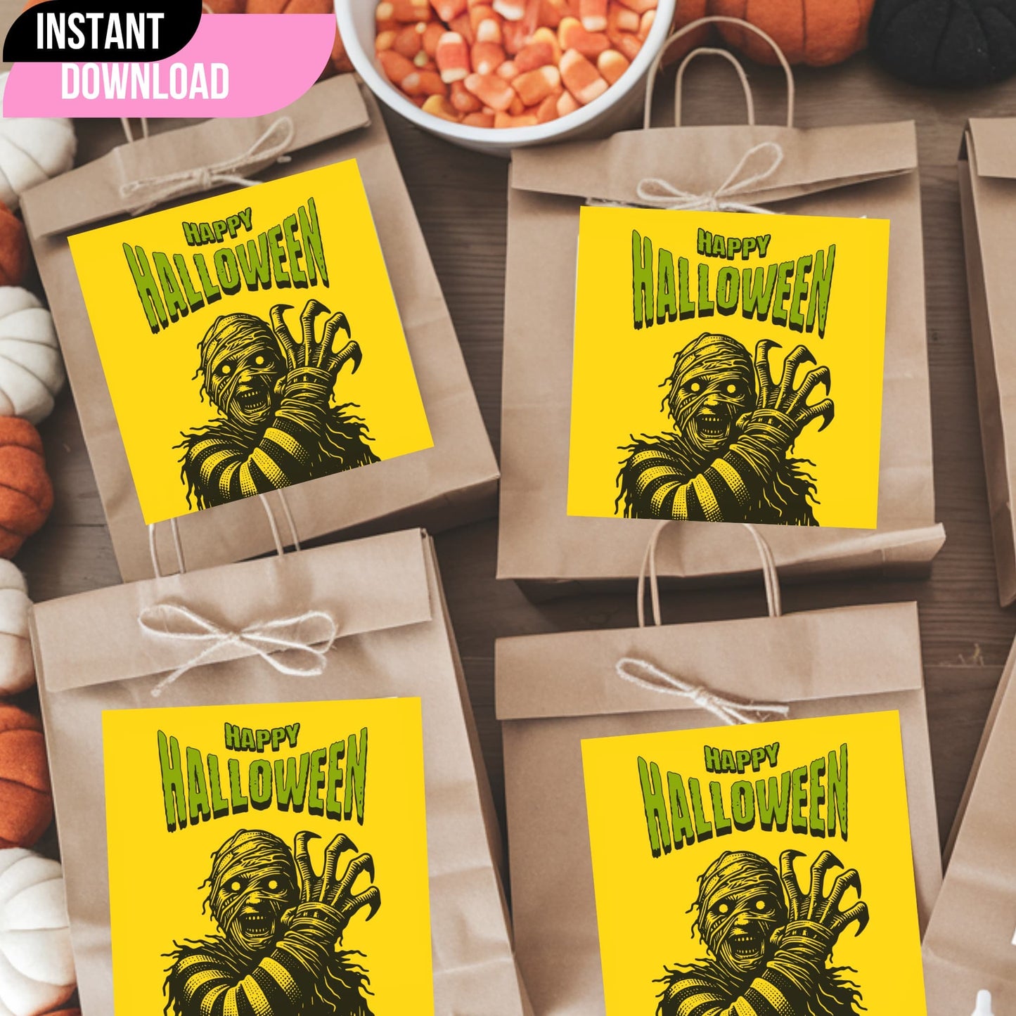 Vintage-style Halloween monster gift tags on kraft paper bags with twine bows, featuring dramatic mummy illustration on yellow background with green lettering, displayed with candy corn and pumpkins