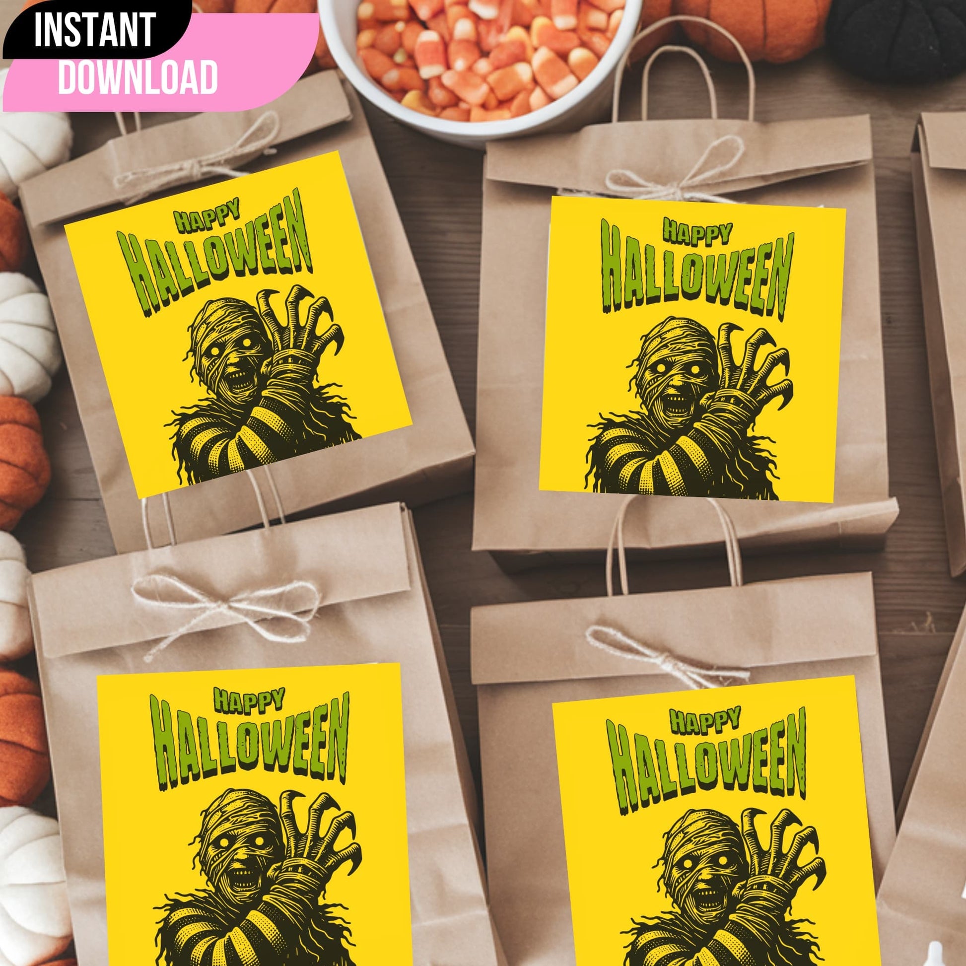 Vintage-style Halloween monster gift tags on kraft paper bags with twine bows, featuring dramatic mummy illustration on yellow background with green lettering, displayed with candy corn and pumpkins