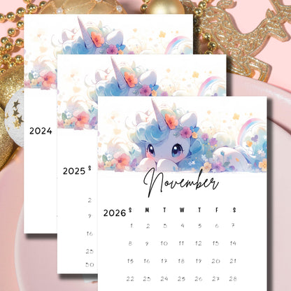 Layered November calendars with watercolor unicorn illustration, pastel flowers and rainbow accent, displayed with golden holiday decorations