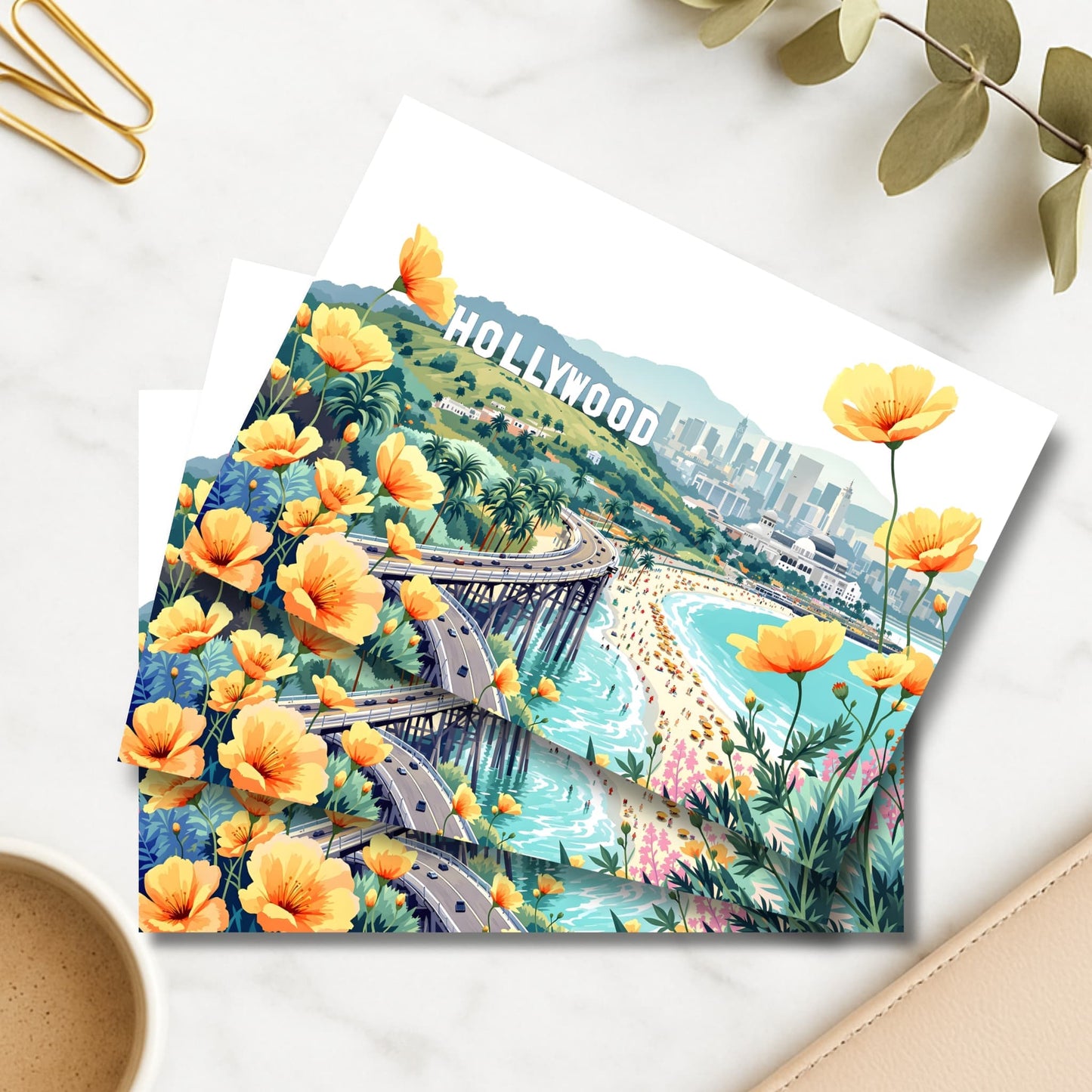 Hollywood illustrated art print with orange California poppies and beach pier beside coffee and gold clips