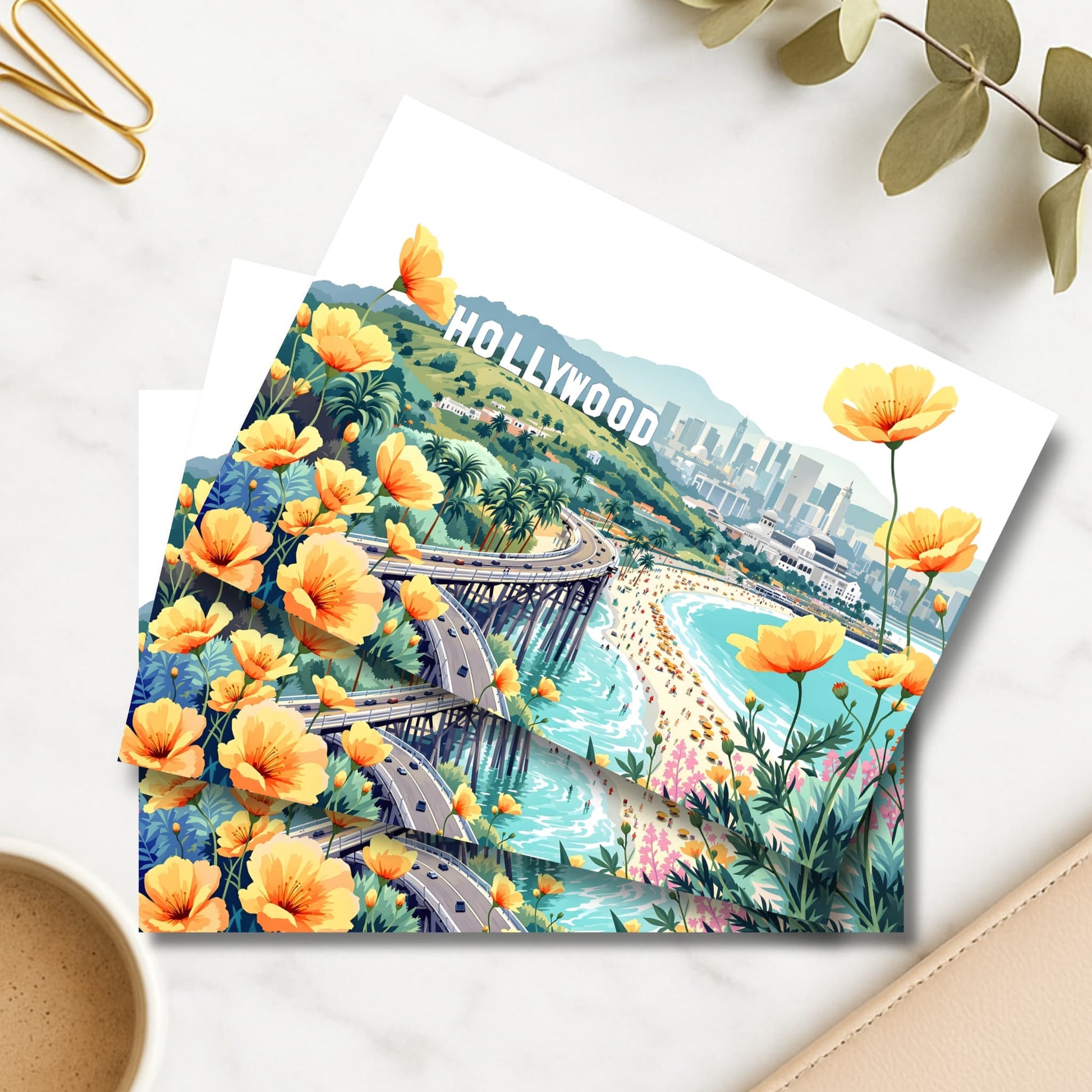 Hollywood illustrated art print with orange California poppies and beach pier beside coffee and gold clips
