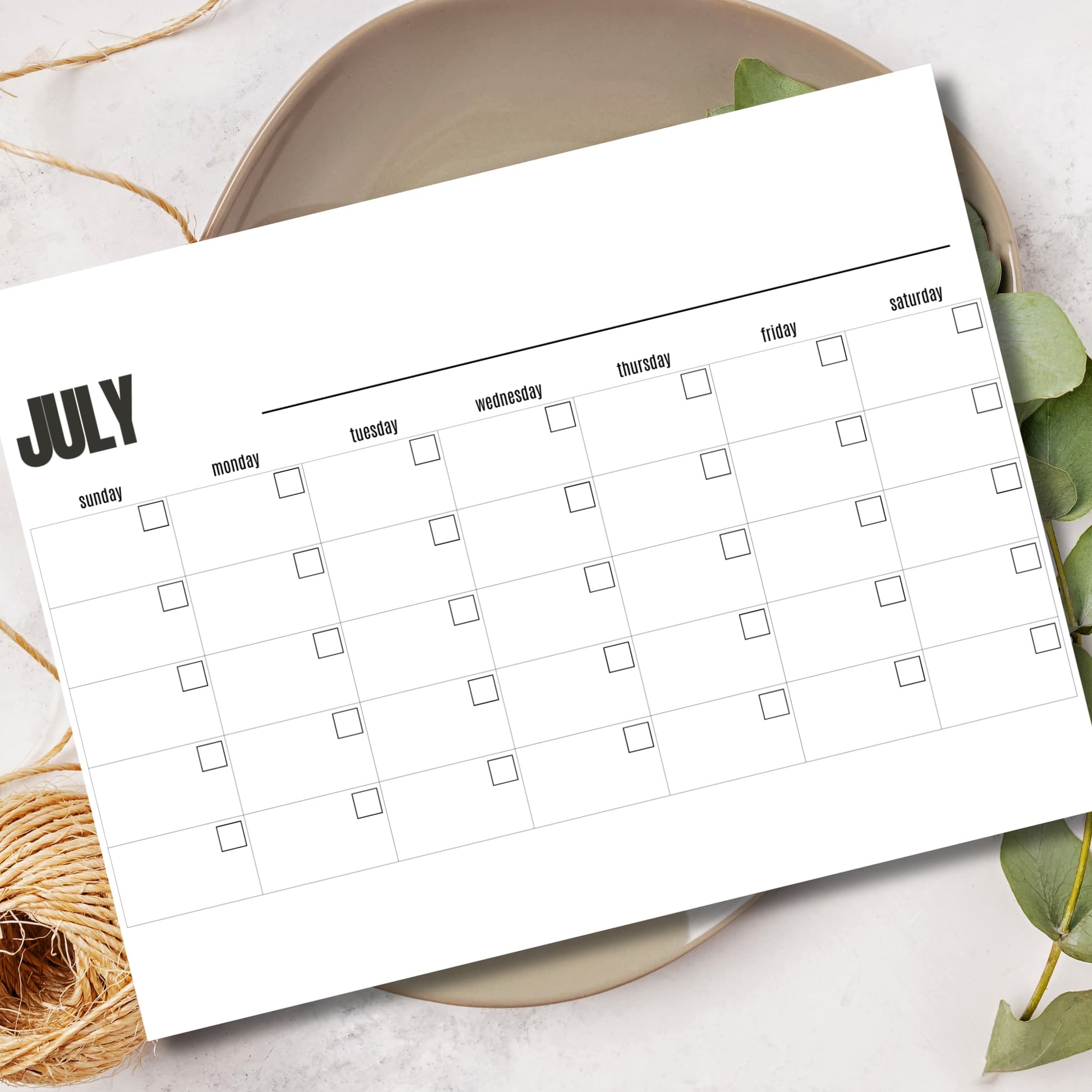 Horizontal layout monthly planner A4 letter size July calendar displayed in ceramic bowl with leaves