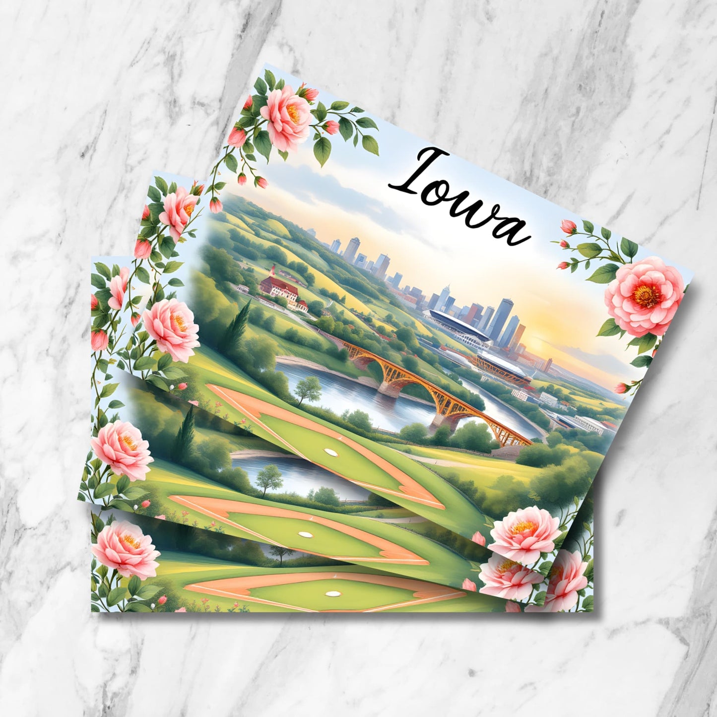 Vintage-style Iowa postcard featuring picturesque golf course with rolling hills, historic bridge, and Des Moines skyline at sunset. Pink wild roses frame the scenic landscape, showcasing the blend of urban and recreational landmarks.