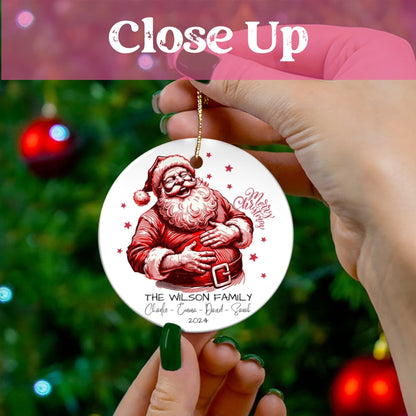 Close-up of personalized ceramic Christmas ornament showing laughing Santa illustration and custom family names against decorated tree backdrop.