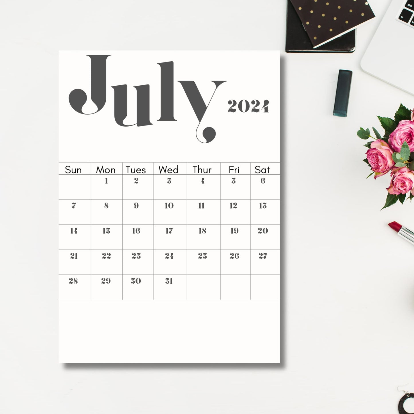 July 2024 printed calendar sheet on the grey table with office accessories beside it.