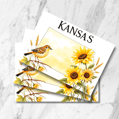 Stack of Kansas state postcards featuring watercolor illustration of state bird meadowlark with sunflowers and wheat, shown on marble surface