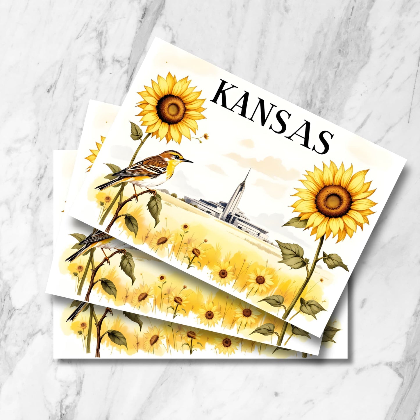 Stack of Kansas postcards featuring watercolor illustration of Kansas City Temple amid sunflower field with meadowlark, displayed on marble background