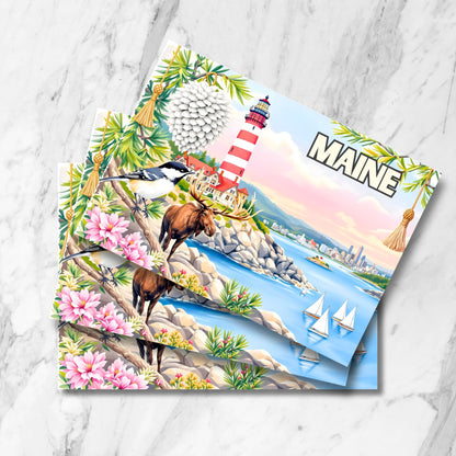 Maine red-striped lighthouse postcards with moose and chickadee. Multiple cards on marble background featuring pine cone and coastal wildlife illustrations.