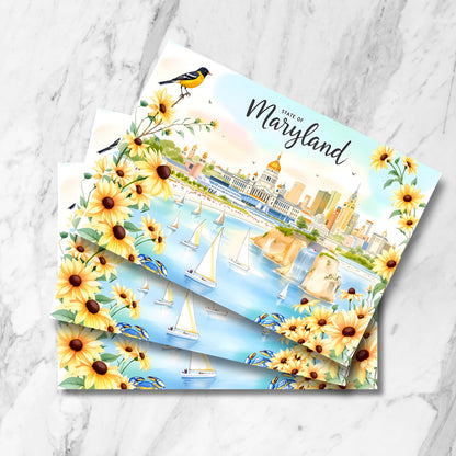 Maryland postcards featuring Baltimore skyline, oriole bird and black-eyed Susans. Multiple cards stacked on marble background showing harbor with sailboats.