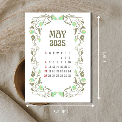 May 2025 calendar page with mint green floral Art Nouveau border, showing 8.5 x 11 inch dimensions, displayed on neutral linen background with wooden bowl