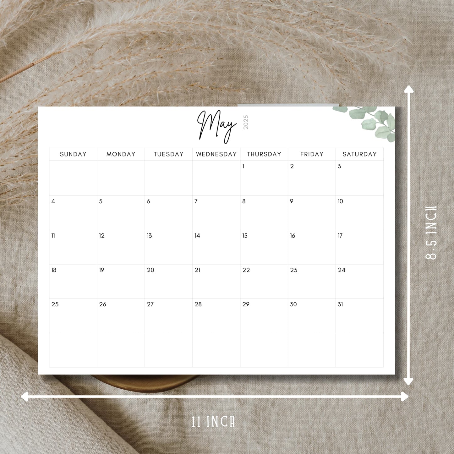 May 2025 minimalist calendar showing 11x8.5 inch dimensions, featuring clean typography, eucalyptus corner detail, displayed on natural linen backdrop