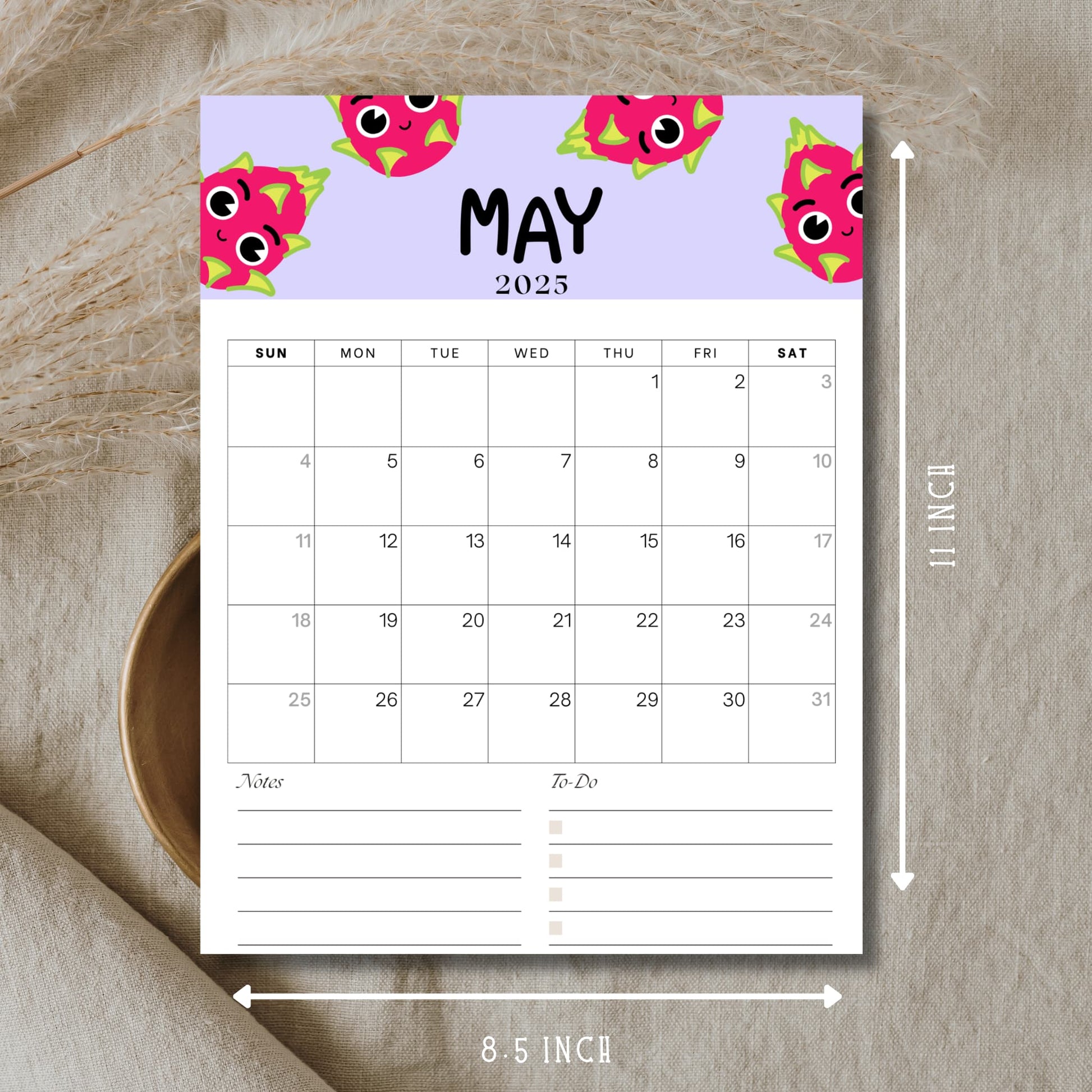 May 2025 printable calendar page with pink dragon fruit illustrations showing dimensions of 8.5×11 inches. Features complete month grid with dates 1-31, notes and to-do sections, displayed on natural linen background.